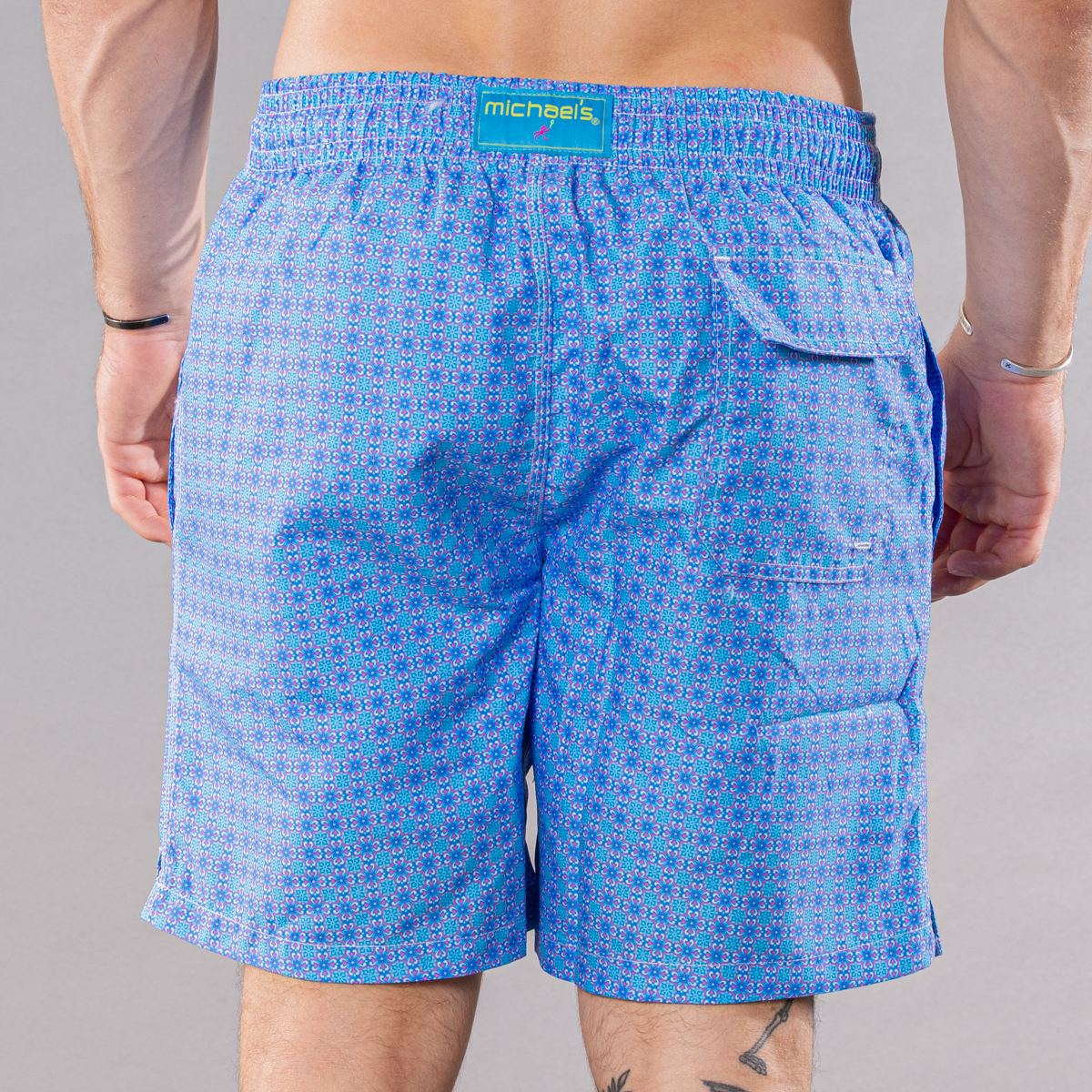 Men&#39;s blue/coral swim trunks with ethnic tile pattern, back view