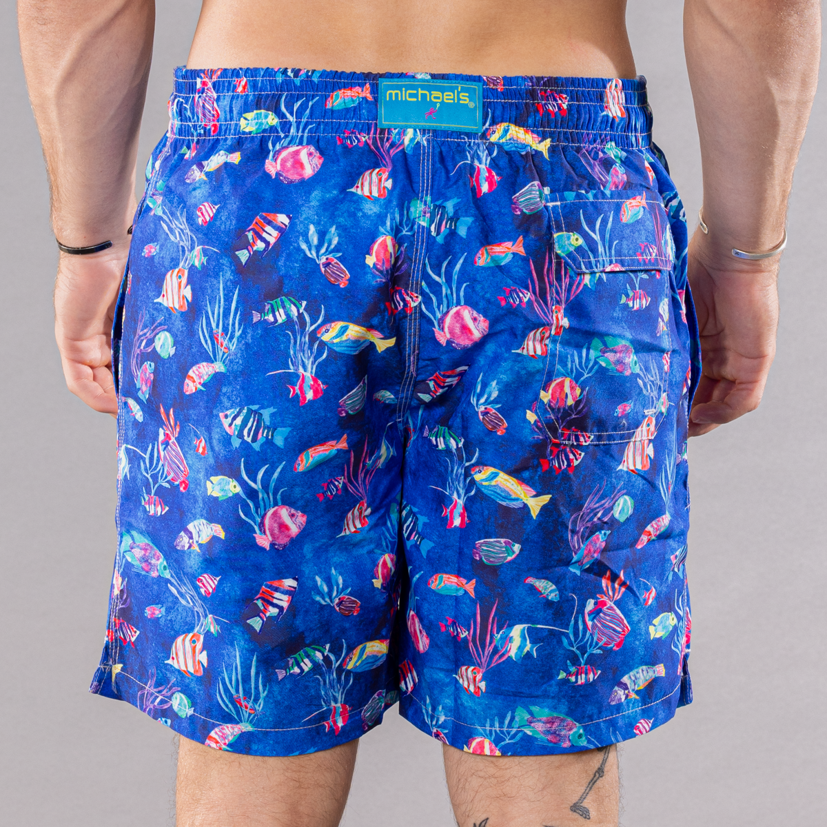 Men&#39;s blue swim trunks with cyclist liner, tropical reef pattern, back view