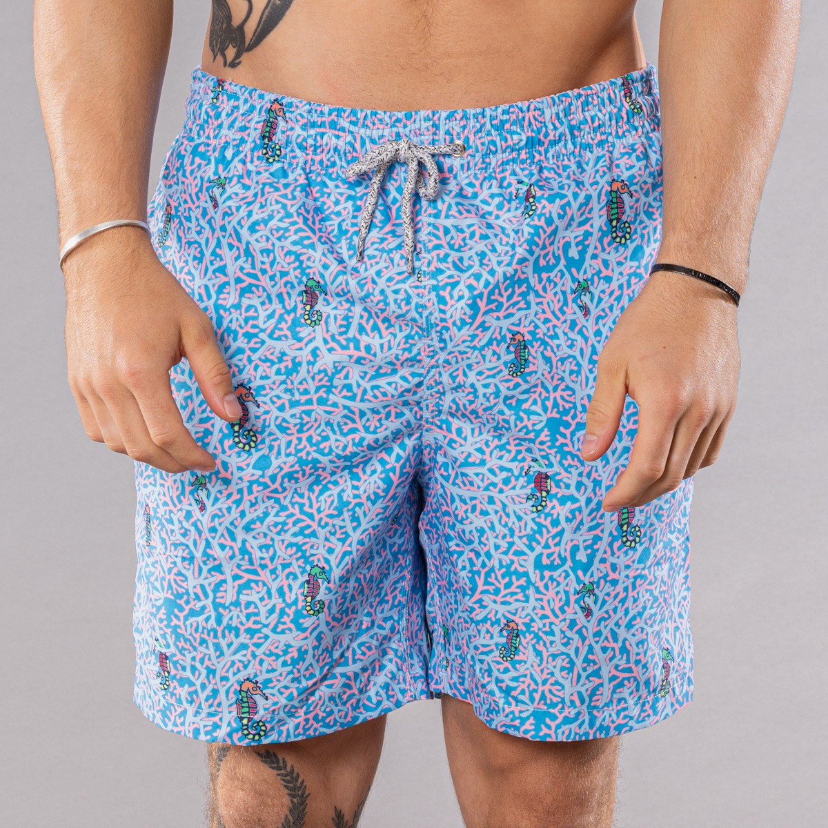 Men&#39;s blue swim trunks with rainbow seahorses pattern, front view