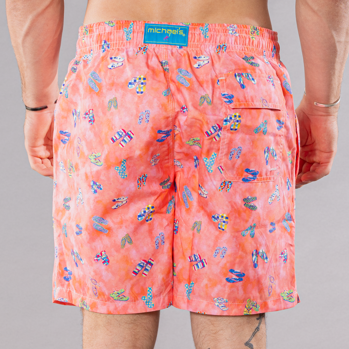 Men&#39;s coral swim trunks with flip flops pattern, back view