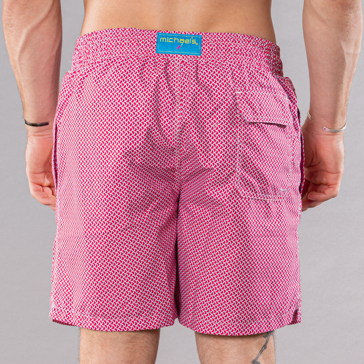 Men&#39;s coral/turquoise swim trunks with wave pattern, back view